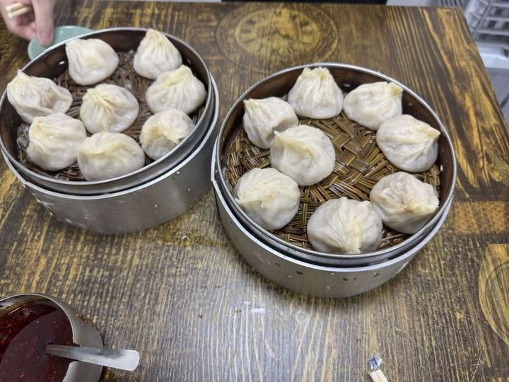 Two baskets of soup dumplings and a pot of chili oil