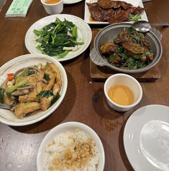 A table of Taiwanese dishes: three-cup, fried tofu, greens and braised pork rice
