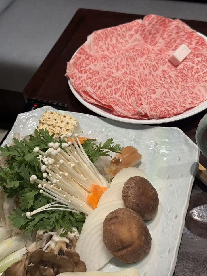 Marbled wagyu slices and a plate of mushrooms and vegetables